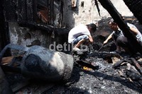 Dua orang warga mencari barang yang masih bisa diselamatkan di antara puing-puing sisa kebakaran.