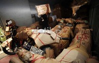 Seorang pegawai menata paket motor yang akan dikirim.