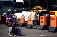 Seorang pemudik dengan menggendong anaknya menuju bus yang akan membawanya ke kampung halaman.