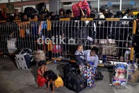 Seorang ibu dengan tiga anak, warga Nunukan, Kalimantan Timur, yang hendak mudik ke Jeneponto, Sulawesi Selatan, sedang menunggu jemputan keluarganya, di areal Pelabuhan Makassar. Muhammad Nur Abdurrahman/detikcom.