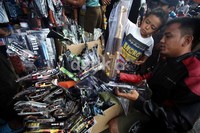 Seorang anak yang didampingi orangtuanya memilih senjata mainan yang akan dibeli.