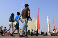 Beberapa pengunjung berjalan di pinggir danau monumen Ancol. Di hari terakhir libur lebaran, pengunjung mencapai 99.515 orang.