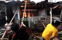 Agar api tidak merembet, sejumlah warga merubuhkan atap rumah yang terbakar.