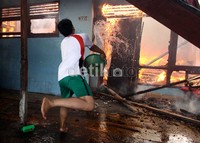 Seorang warga membantu memadamkan api menggunakan ember.