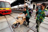 Seorang petugas ekspedisi pengiriman paket barang, menuntun sepeda motor konsumen yang diambil dari muatan kereta api express di Stasiun Bekasi.