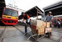 Petugas ekspedisi membantu membawa paket barang milik salah seorang warga.