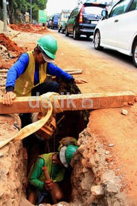 Beberapa pekerja melakukan penggalian.
