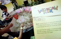 Tampak seorang anak sedang asyik menangkap ikan di areal kolam yang disediakan di sebuah atrium mall.