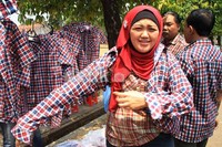 Seorang pembeli mencoba baju kotak-kotak. Baju ini dijual dengan harga Rp 80.000