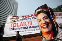 Seorang pendemo berorasi sambil memakai topeng bergambar Hillary Clinton.