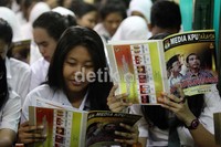 Dua orang siswa membaca selebaran yang berisikan riwayat calon gubernur DKI Jakarta.
