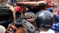 Beberapa warga berusaha mengevakuasi sopir truk yang tergencet.
