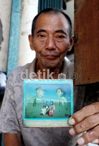 Otong menunjukan foto dia bersama keluarganya.