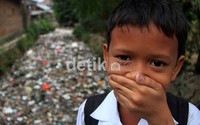 Seorang anak menutup hidungnya karena tumpukan sampah tersebut menimbulkan bau tidak enak.