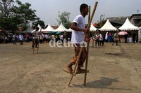 Warga lomba berlari menggunakan enggrang.
