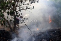 Seorang warga memadamkan api menggunakan peralatan seadanya.