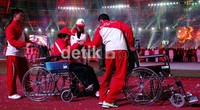 Salah satu mantan atlet putri PON 1 Solo, dipandu dengan kereta dorong, saat mengikuti defile.