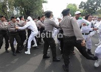Polisi berusaha menghadang massa FPI yang berusaha menerobos pagar betis polisi.
