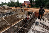 Dua pekerja tengah menyelesaikan pekerjaan aliran air melalui box culver untuk mengatasi banjir di daerah tersebut.