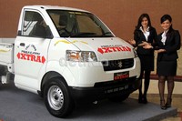 Model berpose di depan mobil Suzuki Mega Carry Extra.