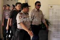 John Kei meninggalkan ruang sidang dengan pengawalan beberapa polisi.