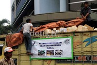 Petugas menurunkan obat dan makanan ilegal dari atas truk untuk dimusnahkan.