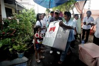 Sebuah kotak suara diamankan ke rumah penduduk karena terkena air hujan.