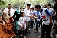 Setelah berjalan sekitar 100 meter, Foke tiba di TPS 01. Di TPS itu, Foke sudah disambut belasan simpatisan yang memakai kaos bergambar hati dan kumis di bagian dada.