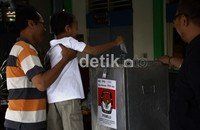 Seorang pemilih meminta anaknya untuk memasuk surat suaranya ke kotak bilik suara seusai menyoblos. Ramses/detikcom.