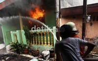 Petugas pemadam kebakaran berupaya memadamkan api yang berkobar di rumah warga.