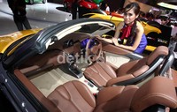 Seorang model berpose dengan Daihatsu D-R. Mobil tersebut atapnya bisa buka-tutup seperti roadster pada umumnya.