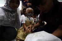 Pembimbing membantu anak-anak ini membatik.