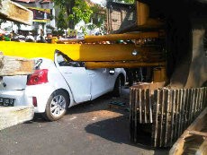 Ekskavator Jatuh dari Truk dan Timpa Mobil Yaris di Makassar