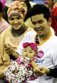 Indra terlihat bahagia saat menggendong Dafani yang menggemaskan dengan pita pink besar di kepalanya.