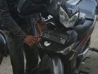 Dengan tang, pengendara ini tengah memasang pelat nomor. (Foto: Win Ruhdi Bathin)