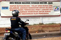 Seorang pemotor melintas di depan spanduk tuntutan yang dipasang di sekitar pabrik.