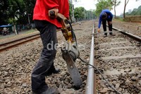 Petugas melakukan penambalan balas atau batuan kerikil pada bantalan rel kereta api.