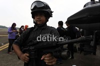 Seorang anak mengenakan helm dan senjata milik TNI.