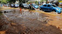 Kendaraan melintas di genangan air akibat pipa PAM yang bocor.