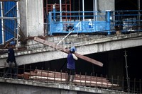 Seorang pekerja menata balok-balok kayu yang akan digunakan untuk menyelesaikan pembangunan gedung.