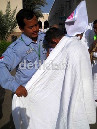 Petugas sektor Bir Ali, Andi Sarwoko membantu jamaah mengenakan pakain ihram dengan baik dan benar.