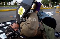 Seorang peserta aksi meniup seruling dengan posisi yang unik.