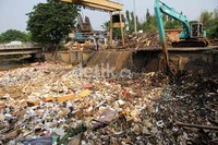 Petugas membersihkan sampah yang menggunung untuk memperlancar aliran air sungai Ciliwung.