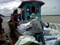 Petugas Bea Cukai menurukan karung-karung yang berisi pakaian bekas dari atas kapal kayu.