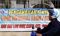 Seorang pengendara motor melintas di depan spanduk bertuliskan Pengambilan e-KTP Gratis yang dipasang di Kelurahan Palmerah, Jakarta Barat.