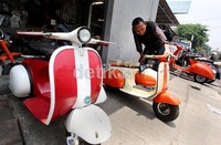 Seorang pengunjung melihat-lihat Vespa mini yang didisplay di depan bengkel Vespa, Jalan Palmerah Raya, Jakarta Barat, Selasa (16/10/2012).