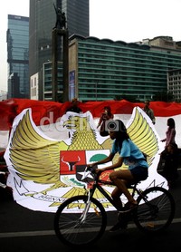 Seorang pengendara sepeda melintas di depan burung Garuda dan bendera Merah Putih yang dibentangkan. (Ramses/detikcom).