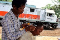 Jamal (47) mencukur rambut pelanggannya di kekas Stasiun Mampang, Menteng, Jakarta Pusat.