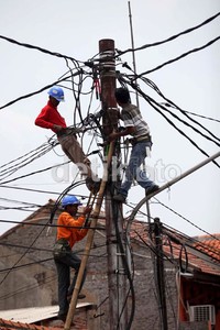 Tiga orang petugas memanjat tiang listrik untuk mengecek jaringan.