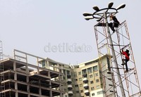Beberapa pekerja memperbaiki lampu penerangan jalan umum (PJU) di Jalan Gelora, Senayan, Jakarta.